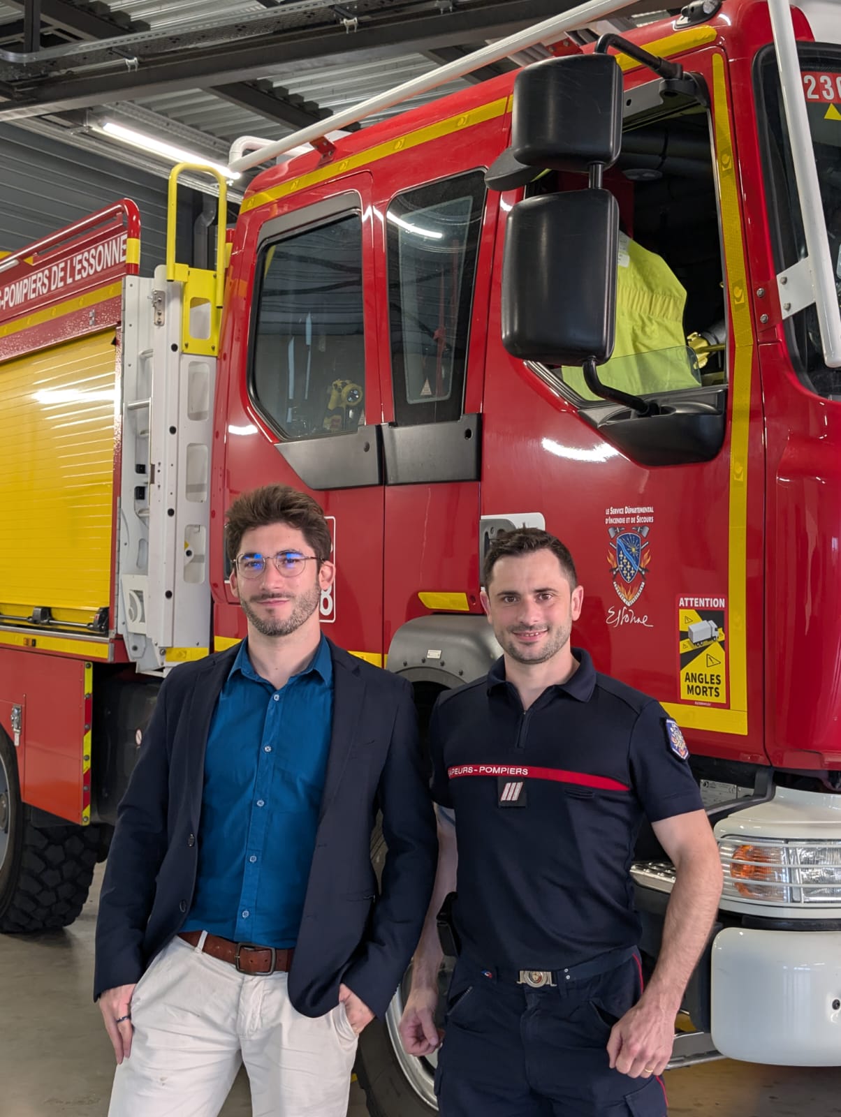 Deux personnes devant un engin des sapeurs-pompiers de l’Essonne, dans un centre de secours